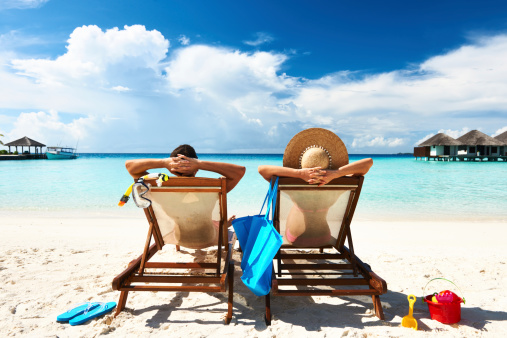 Férias chegando? Crie uma mensagem de ausência temporária engraçada - foto mostra casal descansando na praia. 