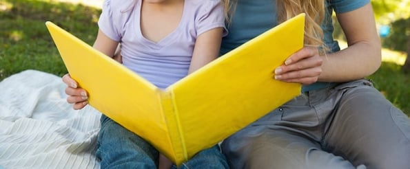 personne entrain de lire un livre à son enfant