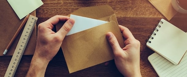 Person oeffnet einen Briefumschlag als Symbol fuer eine Vertriebs-E-Mail