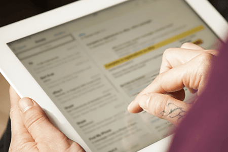 Person schaut sich E-Mail-Betreffzeilen auf Tablet an