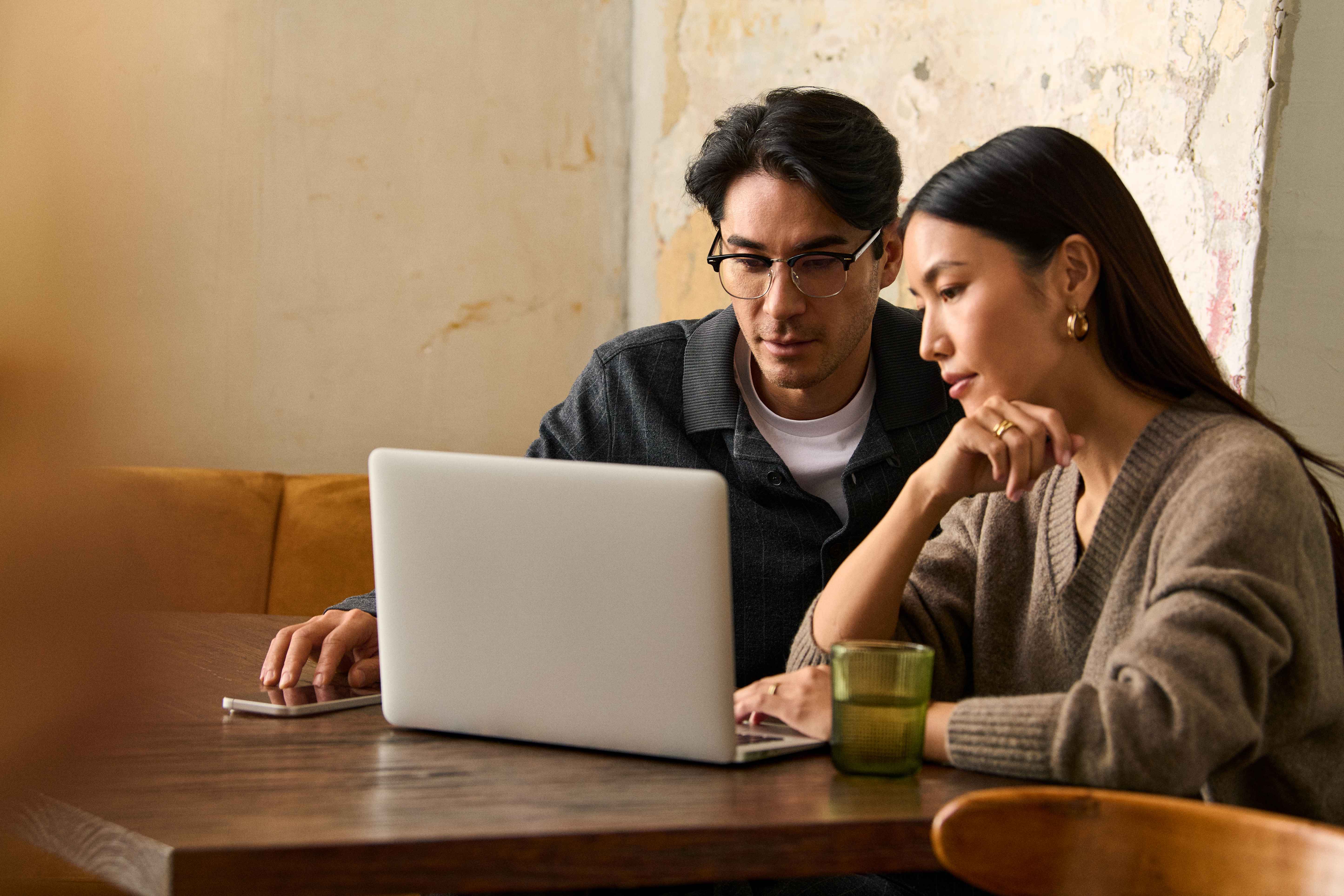 2 people working together while looking into a laptop screen