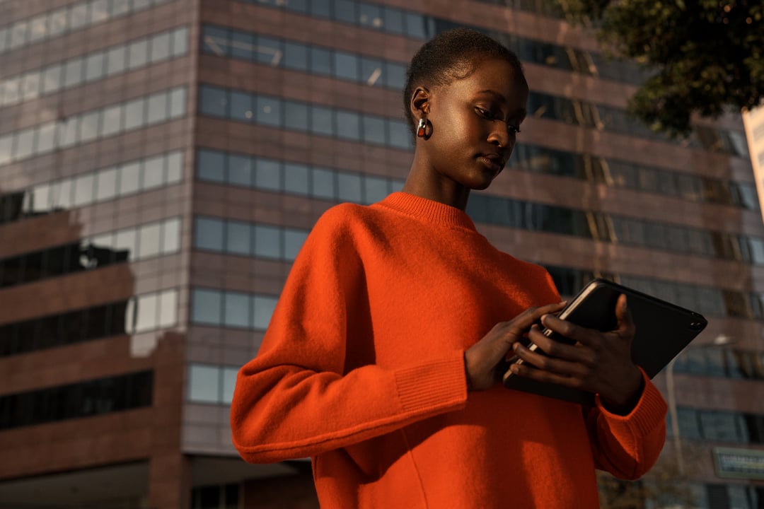 Woman with iPad on street orange sweater