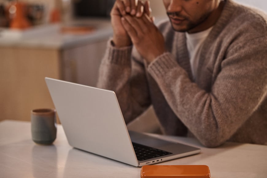 Man in kitchen with laptop and phone