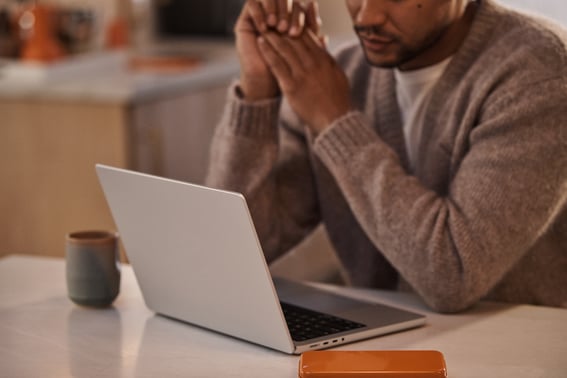 Man in kitchen with laptop and phone