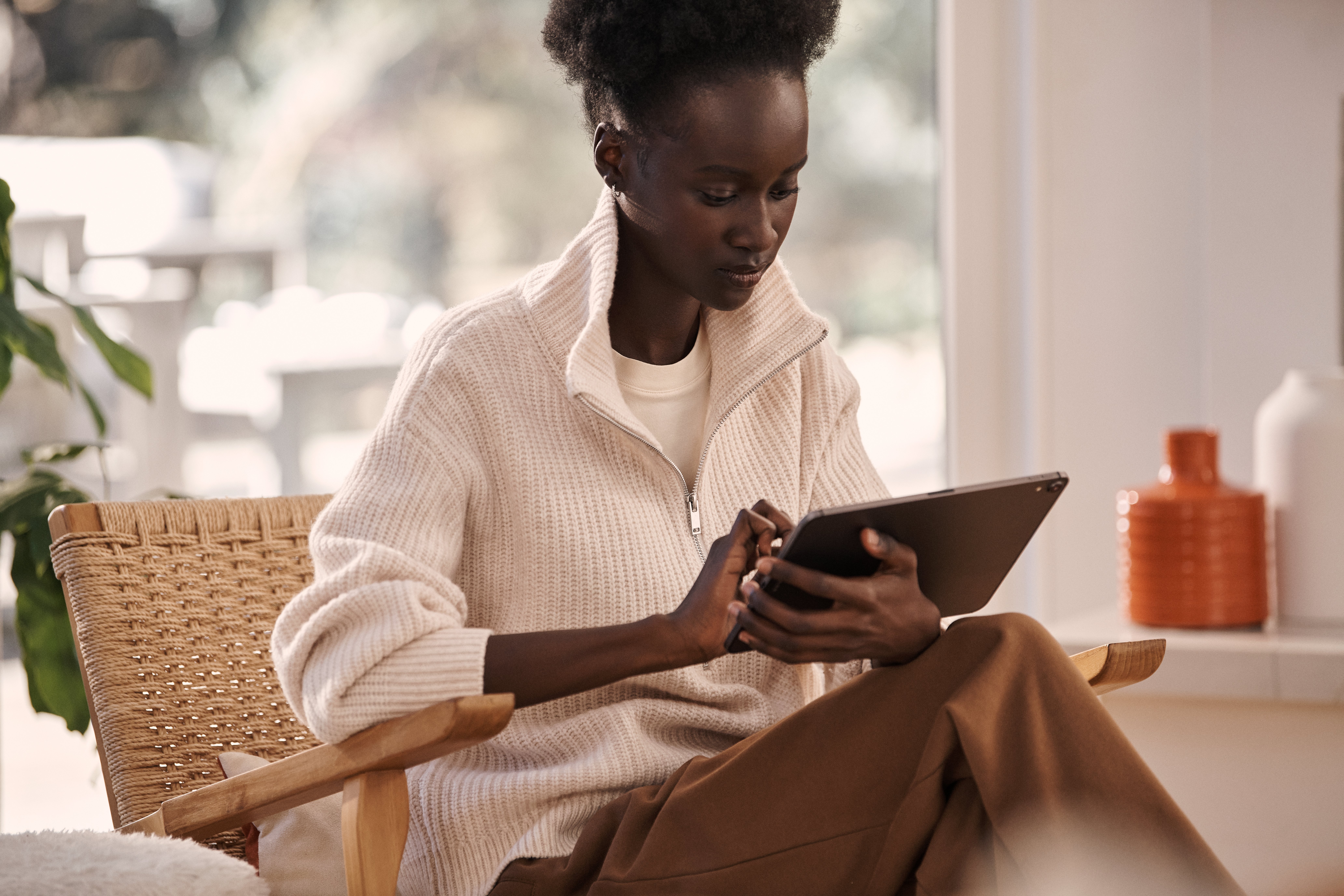 Frau mit iPad auf einem Sessel im Wohnzimmer