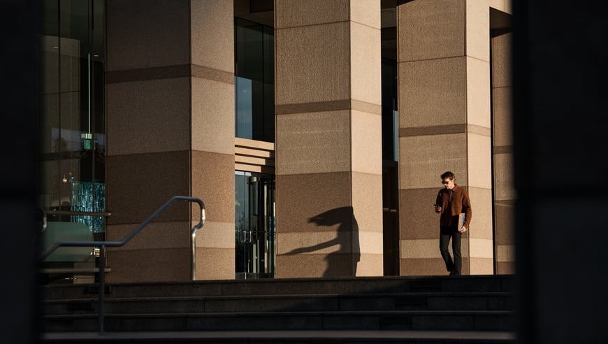 Wide shot man walking outdoors with phone