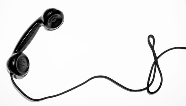 Black phone receiver with long cord against white background