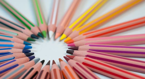 A rainbow of colored pencils arranged in a circle, tips point inward
