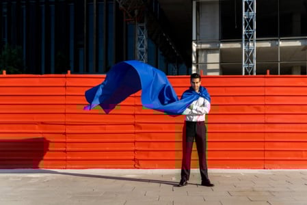 Ein Mann in Business-Kleidung und einem Umhang als Symbol für den Archetypen der Held