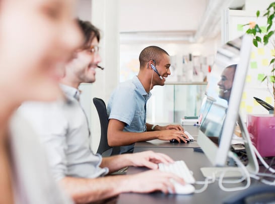 Kundenservice-Mitarbeiter im Hintergrund telefoniert und arbeitet an Computer