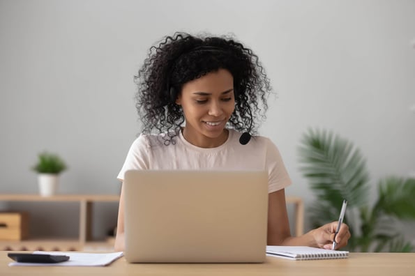 Frau sitzt am Laptop mit Headset