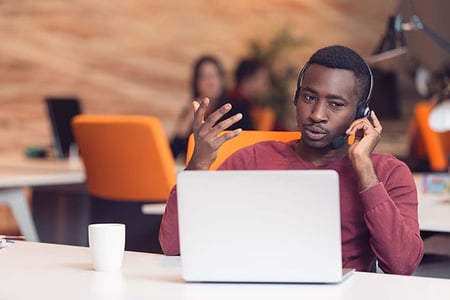 Sales-Mitarbeiter telefoniert und nutzt CRM-Anwendung auf Laptop