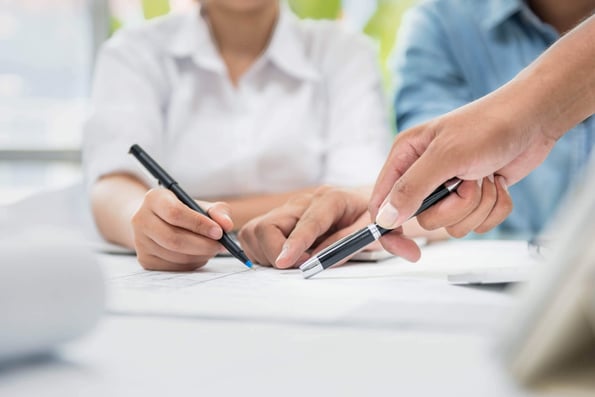 Finger zeigen mit Stiften auf ein Dokument