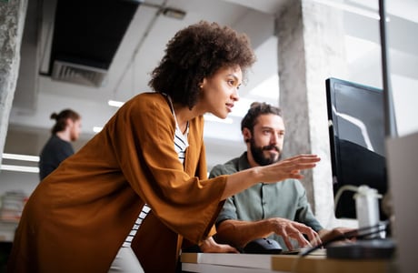 Mann und Frau besprechen etwas vor einem Computer Bildschirm