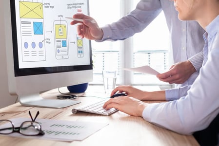 Person zeigt auf interaktives Webseite-Design auf Bildschirm