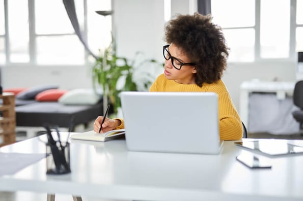 Frau mit Brille arbeitet am Laptop