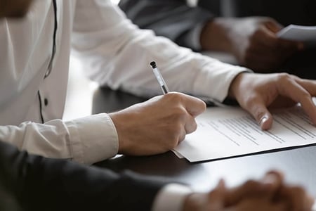Frau unterschreibt Formular zur Markenanmeldung mit Kugelschreiber