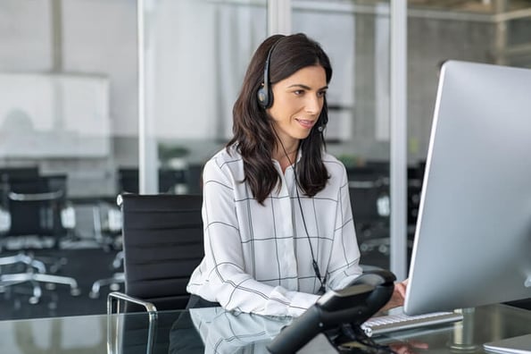 Frau arbeitet am Computer und telefoniert