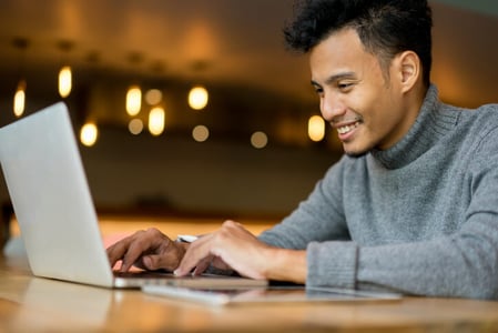 Mann arbeitet mit Laptop an Social Media Kalender