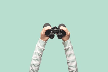 Person-hält-Fernglas-für-visuelle-Suche-hoch