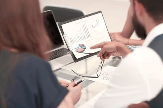 Team sitzt vor Laptop und diskutiert über Preispolitik
