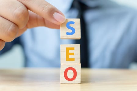 Finger stapeln Holzklötze mit SEO-Schriftzug aufeinander
