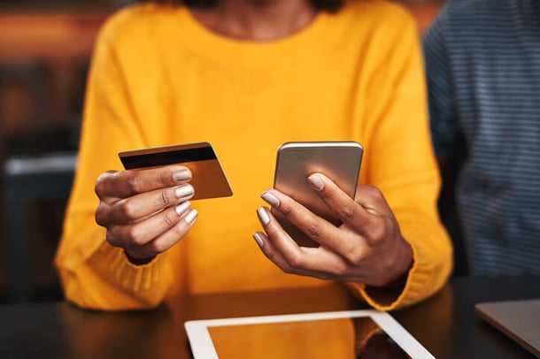 Frau hält Kreditkarte und Smartphone in den Händen