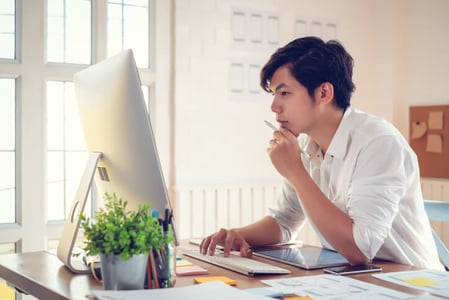Ein Teammitglied sitzt am Arbeitstisch und arbeitet mit einem Website Builder