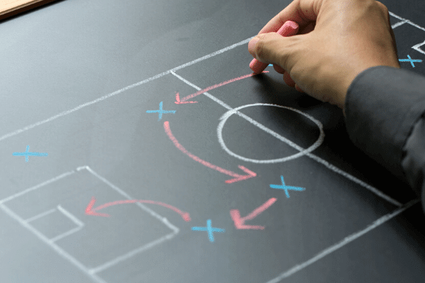 Leitfaden Wettbewerbsanalyse: Mann malt Spielplan des Wettbewerbs auf eine Tafel