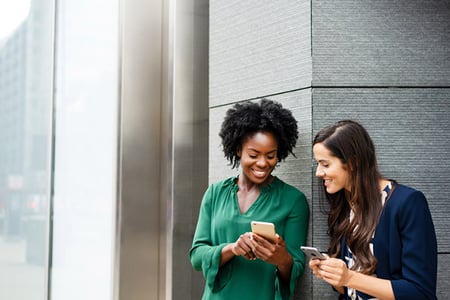 Zwei Frauen an Straßenecke schauen auf BeReal-App auf Smartphones