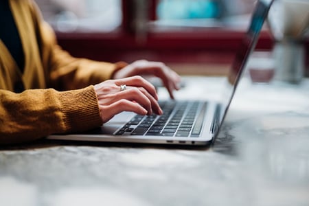 Frau schreibt E-Mail mit Bitte um Rückmeldung am Laptop