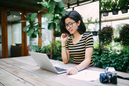 Frau am Laptop im Garten schreibt Blogbeitrag