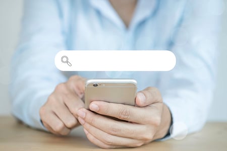 Person sucht auf Handy mit booleschen Operatoren