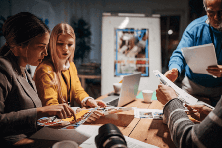 Team sitzt an Tisch und arbeitet an Clickbait-Kampagne