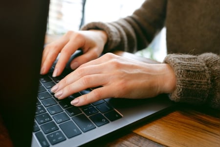 Hände einer Mitarbeiterin, die an einem Corporate Blog arbeitet