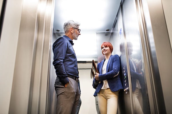 Personen besprechen im Fahrstuhl den Elevator Pitch