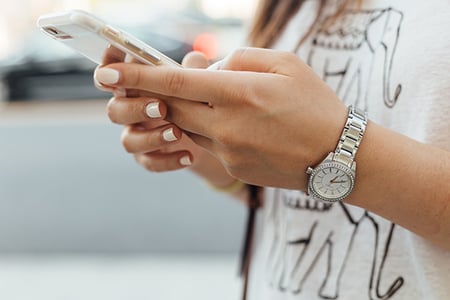 Nahaufnahme Frau erstellt Facebook Carousel Ad am Smartphone