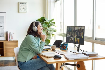 Frau zuhause nimmt an hybridem Event am Computer teil