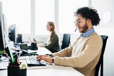 Mitarbeiter sitzt vor PC und schreibt Kundenservice-E-Mail-Vorlage