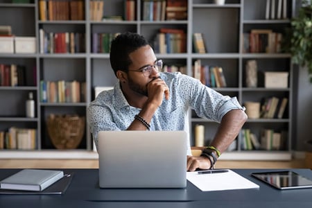 Mann am Arbeitstisch ueberlegt, ob er LinkedIn Premium oder XING Premium nutzen soll