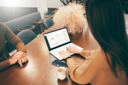 Frau berechnet Marge (Handelsspanne) am Laptop