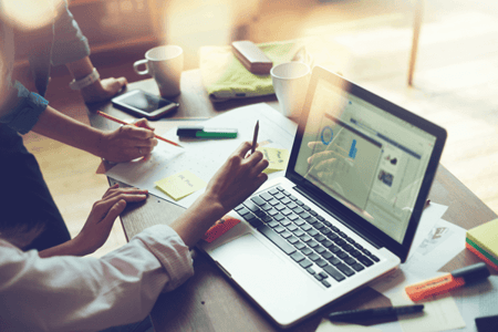 Personen vor Laptop entwickeln B2B-Online-Marketing-Strategie