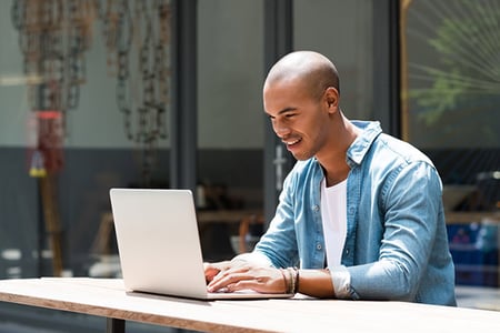 Mann vor Laptop am Tisch verwendet negative Keywords bei Google Ads