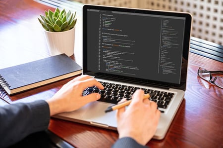 Mann bearbeitet Quellcode einer Website am Laptop