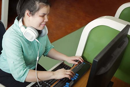 Frau nutzt Screenreader und Braillentastatur