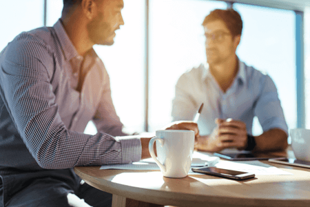 Zwei Männer sitzen am Tisch und reden über Verkaufstechniken