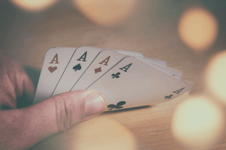 Person hält 4 Asse in der Hand symbolisierend für Verkaufsstrategien