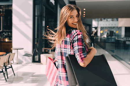 Frau mit Einkaufstueten auf Strasse shoppt dank saisonalem Marketing