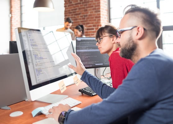 two people using a desktop computer in a office to create a css grid