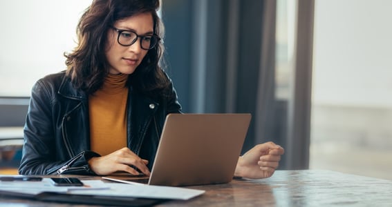 Femme assise à son bureau entrain de travailler sur son ordinateur